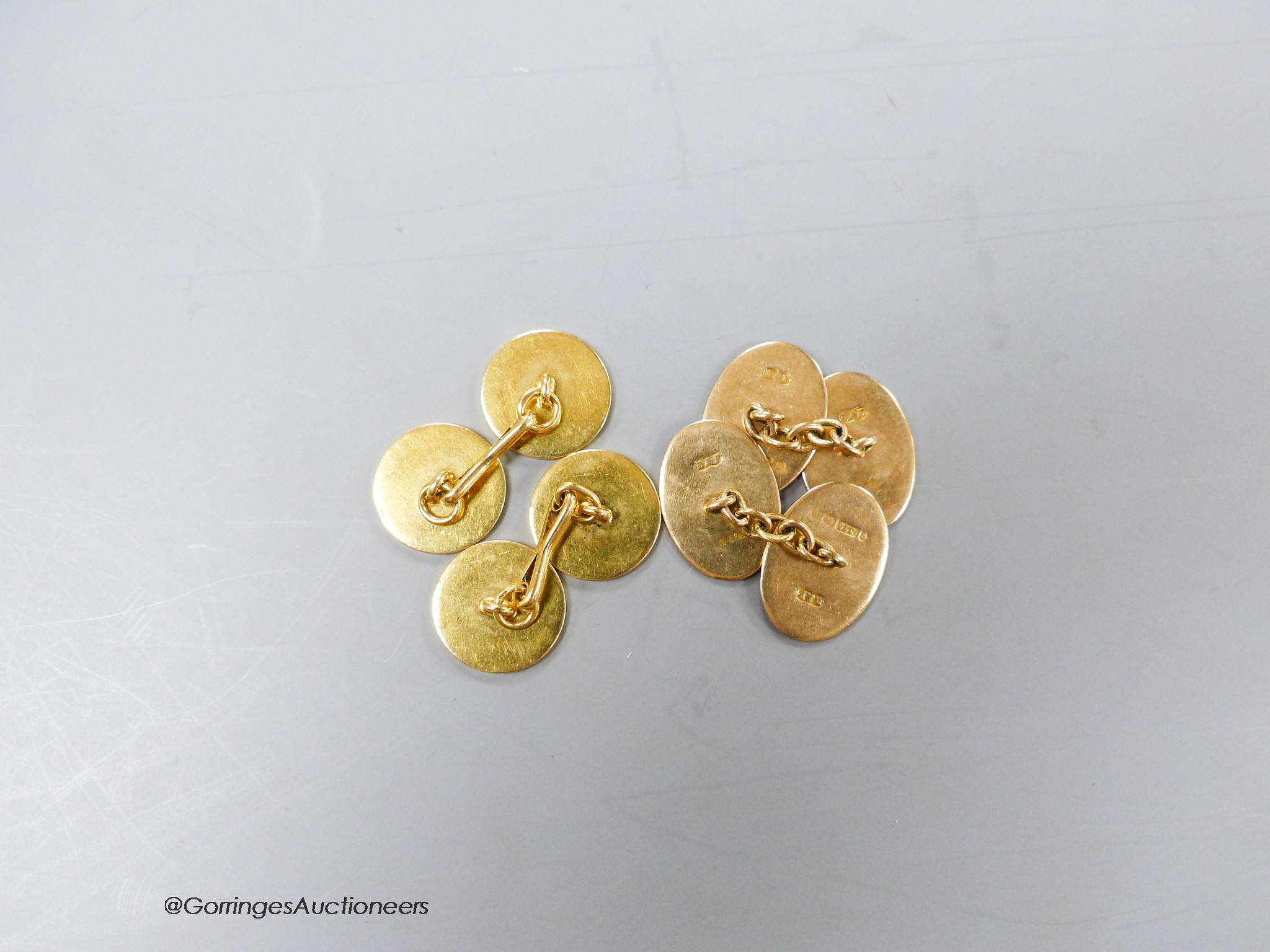 A pair of George V 9ct gold and blue enamel oval cufflinks, with engraved initial, gross 6.6 grams and one other pair of yellow metal disc cufflinks, 12.9 grams.